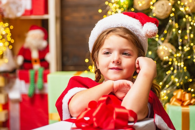 Premium Photo | Little girl in santa costume near a present indoor