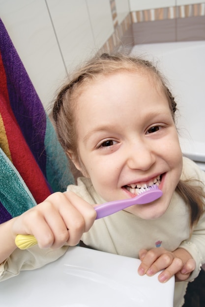 Premium Photo | Little girl screwing up one`s eyes and cleaning a teeth ...