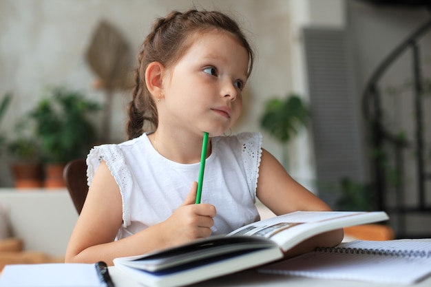 Premium Photo | Little girl sits at the desl at home and does homework ...