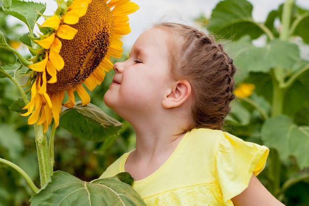 Premium Photo | Little girl smelling a sunflower