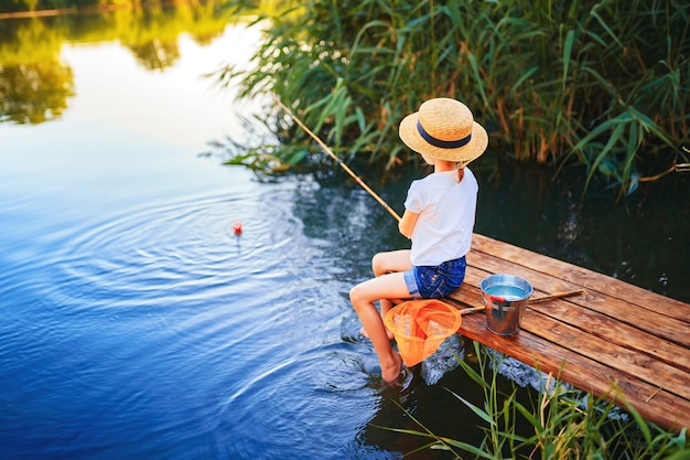 Premium Photo | Little girl in straw hat sitting on the edge of a ...