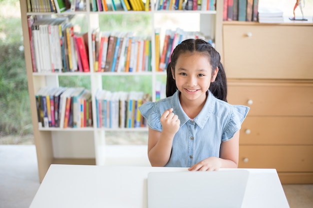 Little Girl Student With Laptop At Desk In Library And Fighto