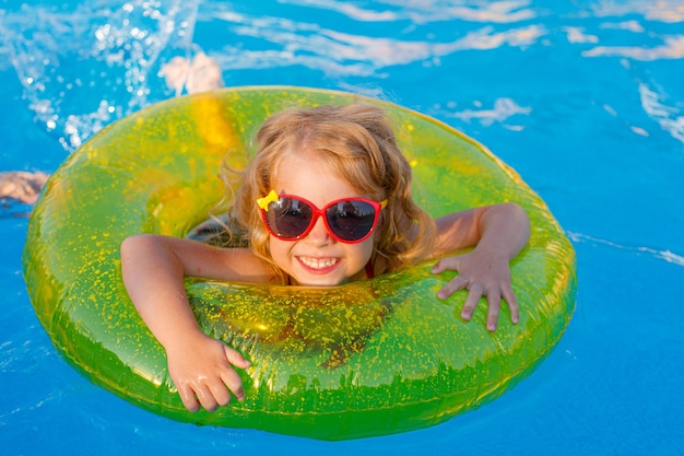 Premium Photo | A little girl in sunglasses and a swimsuit swims in the ...