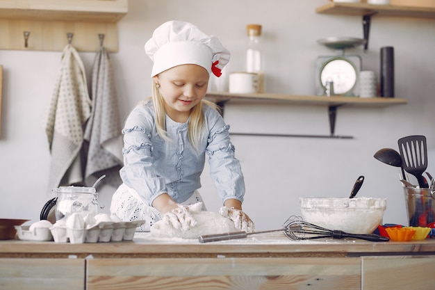 Little girl in a white shef hat cook the dough for cookies Free Photo