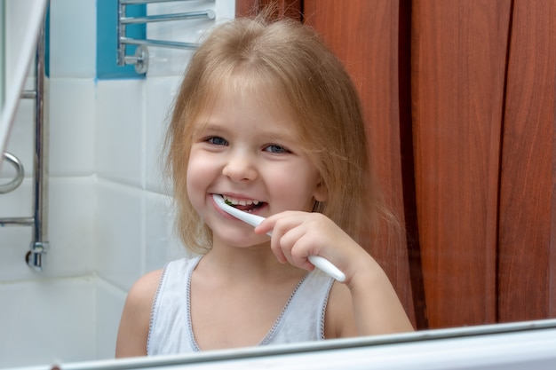 A Little Girl With Blond Hair Brushing Her Teeth Premium Photo