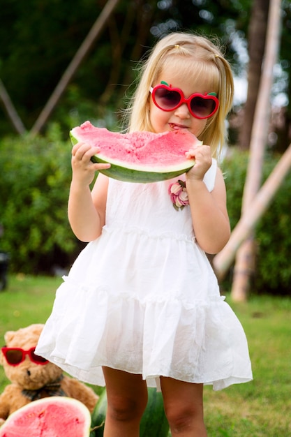 Little Girl With Blonde Hair In Sunglasses Eating Watermelon On