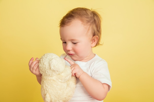 黄色のスタジオの壁に分離されたぬいぐるみを持つ少女 無料の写真