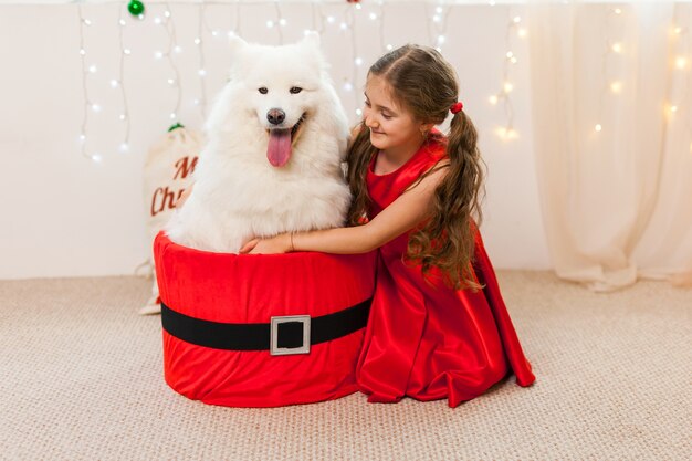 サンタの箱に座っている白いサモエド犬と少女 プレミアム写真