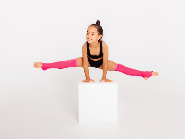 Premium Photo | Little gymnast on a large white cube performs sports ...