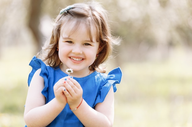 Premium Photo Little Happy Girl In A Blue Dress Plays With Flowers