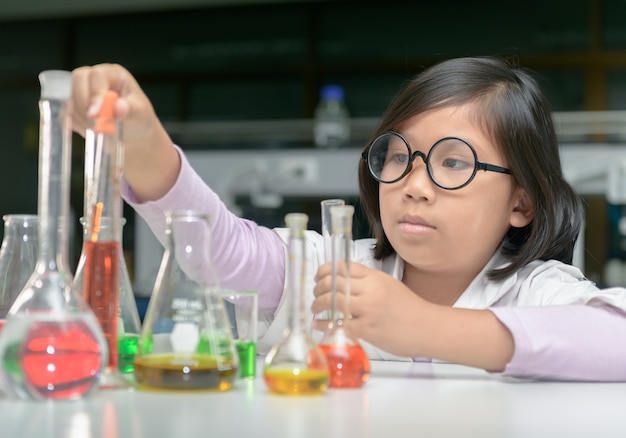 Premium Photo | Little scientist in lab coat making experiment