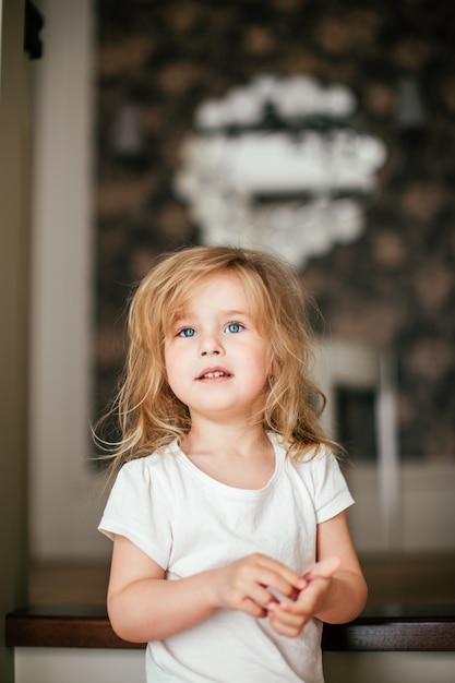 青い目を持つ少し毛むくじゃらの金髪の赤ちゃん女の子は彼女の朝目覚めた後笑っています プレミアム写真