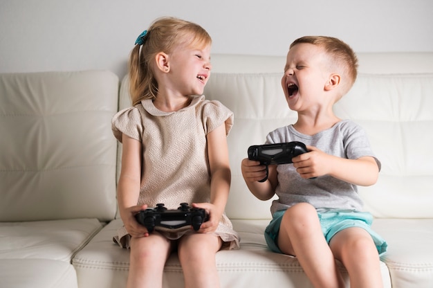 Little siblings playing digital games with joystick Free Photo