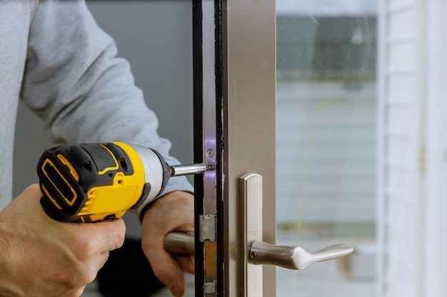 Locksmith hand holds the screwdriver in installing door lock Premium Photo