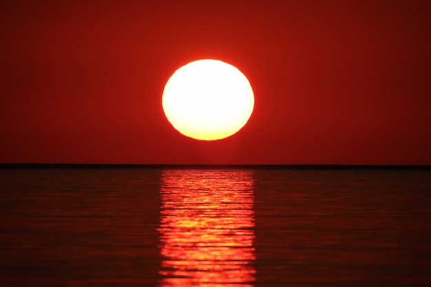 赤い空と太陽を反射する海のロングショット 無料の写真
