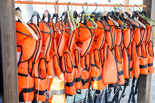 Premium Photo | Lots of orange life jackets hanging on hangers.