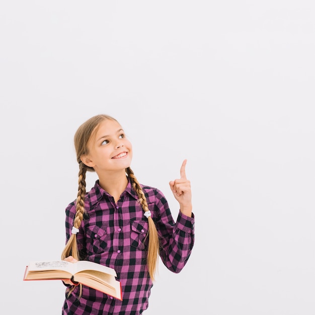 Lovely little girl with a book pointing up Free Photo Lovely little girl with a book pointing up Free Photo