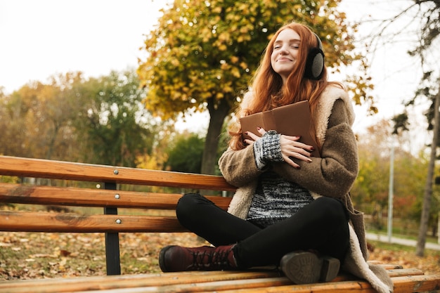 Premium Photo | Lovely redheaded young girl listening to music with ...