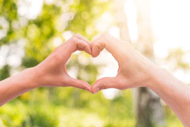 Premium Photo | Lovers gesturing heart sign with hands outside