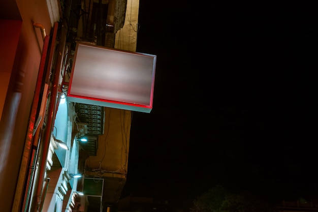 Low angle view of illuminated billboard on residential building against sky Free Photo