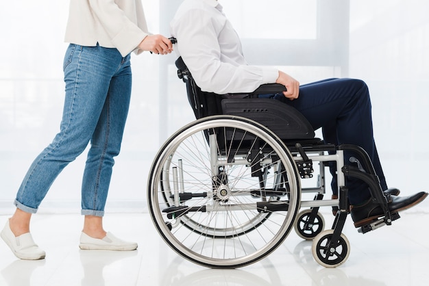 Low section of a woman pushing the man sitting on wheelchair Free Photo