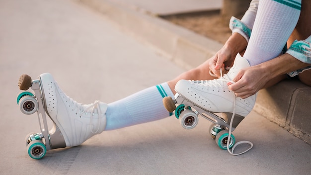 Low section of woman tying lace of roller skate | Free Photo