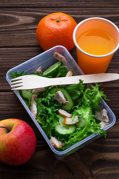 Lunch box with salad, apple, tangerine and juice. Premium Photo