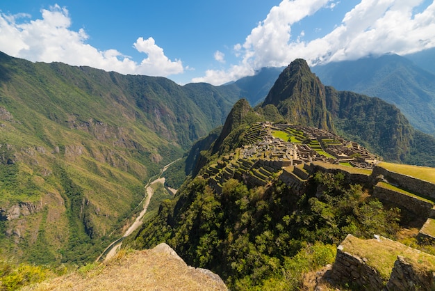 Machu picchu illuminated by the sunlight. wide angle view from the terraces above with scenic sky. Premium Photo