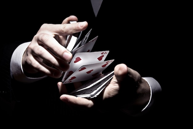 スポットライトの下でクールな方法でカードをシャッフルする魔術師 無料の写真