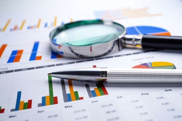 Premium Photo | Magnifying glass on charts graphs spreadsheet paper.