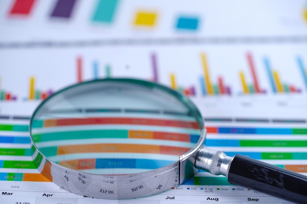 Premium Photo | Magnifying glass on charts graphs spreadsheet paper.