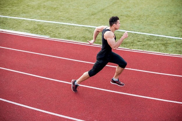Male athlete arrives at finish line on racetrack during training ...