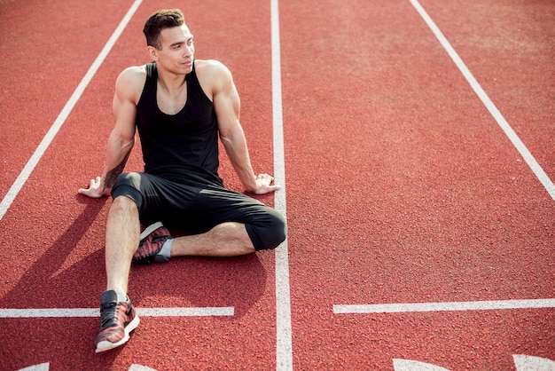 Free Photo | Male athlete relaxing on red race track