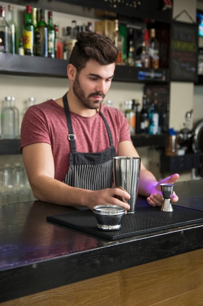 Free Photo Male bartender  adding ingredient in shaker at 