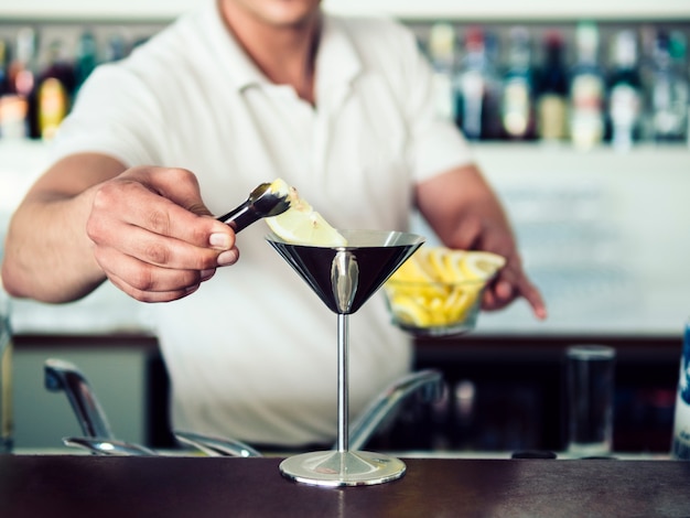 Serving drinks. Бармен с коктейлем в руках. Бармен взбивает мартини картина. Бармен подаёт стакан.