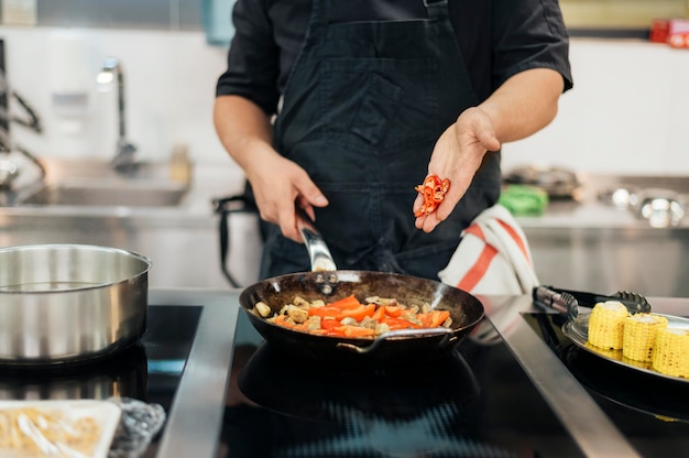 Premium Photo | Male chef adding chili to dish