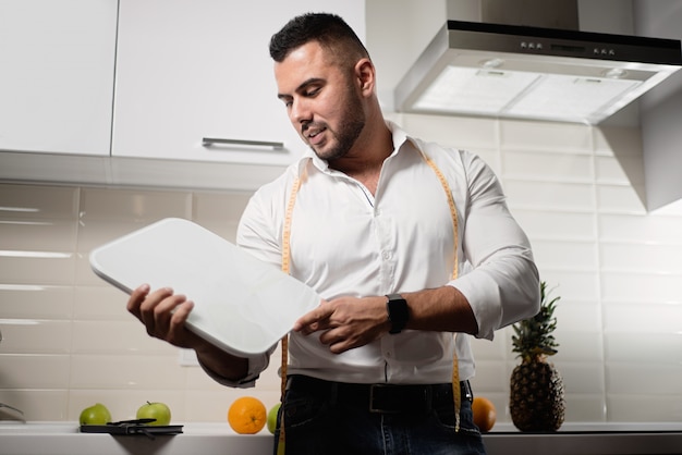 Premium Photo | Male dietitian holding scales in the kitchen.