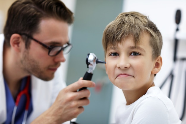 Premium Photo Male Doctor Examining Boys Ear With An Otoscope