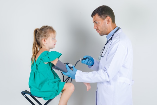 白い制服 手袋で子供の心臓の脈拍を測定する男性医師 無料の写真