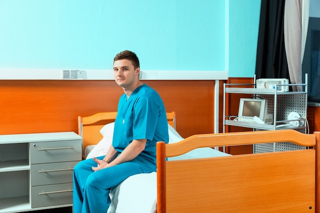 Premium Photo Male Doctor Wearing Uniform Sitting On A Bed And Waiting For His Patient In The