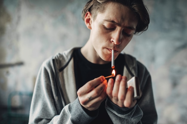 男性の麻薬中毒者がタバコに火をつける プレミアム写真