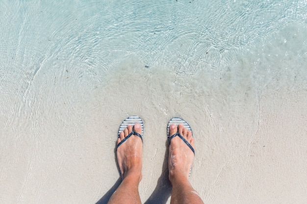 Premium Photo Male Feet Wearing Female Flip Flops At Beach