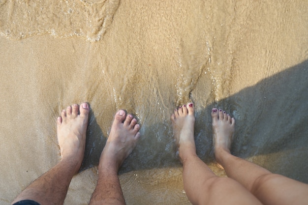 Male and female feet standing on the beach | Premium Photo