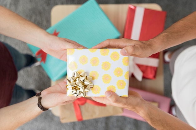 Male Friends Hand Holding Gift Box With Golden Ribbon Bow