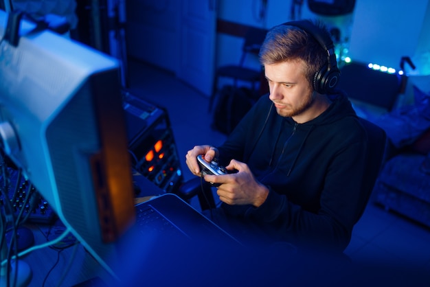 Premium Photo | Male gamer in headphones holds joystick and playing  videogame on console or desktop pc, gaming lifestyle, cybersport. computer  games player in his room with neon light, streamer