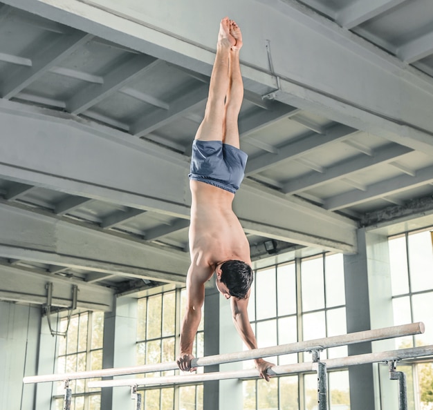 Free Photo Male gymnast performing handstand on parallel bars