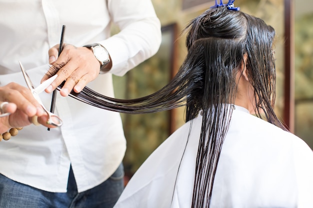 Male hairdresser  cutting  wet hair  of female client Photo 