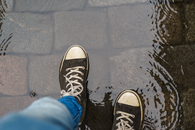 雨の水たまりを歩くスニーカーの男性の足 プレミアム写真