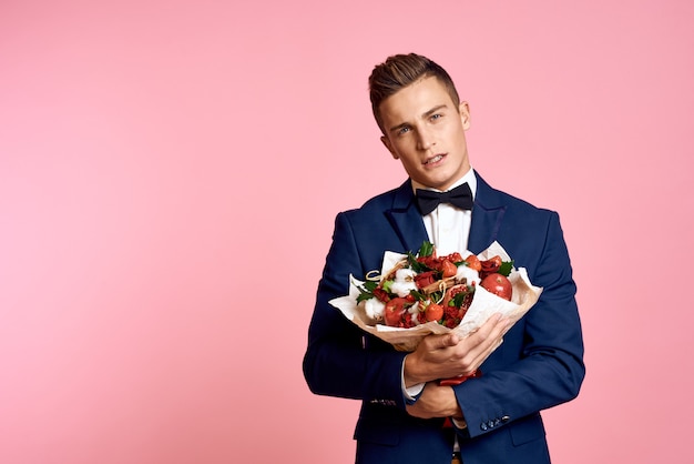 花束を持つ空間でクラシックなビジネススーツでポーズをとる男性モデル プレミアム写真