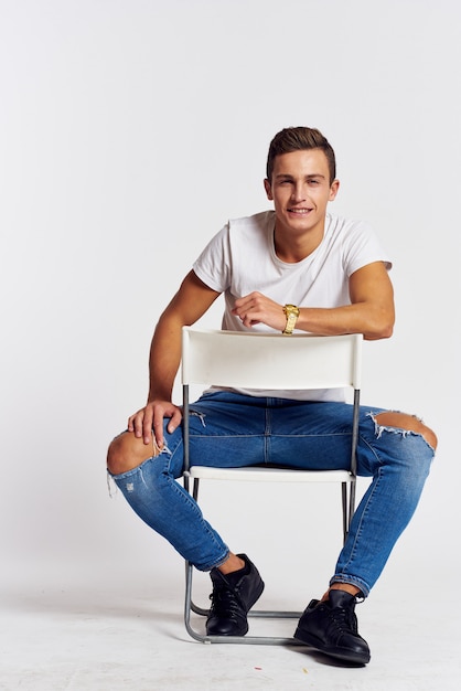 Premium Photo Male Model Posing In Jeans And A White T Shirt On A Light Wall